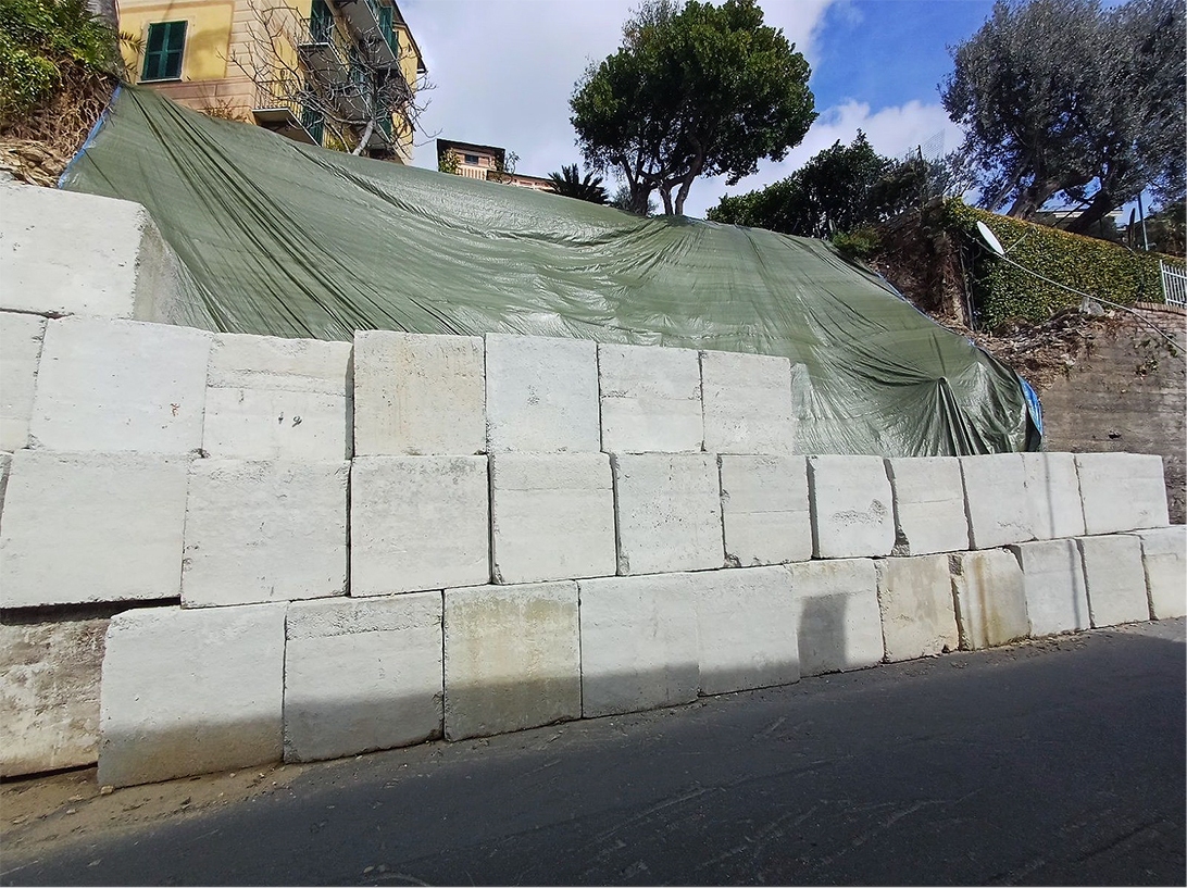 Messa in sicurezza provvisoria: blocchi in calcestruzzo e telo di contenimento.
